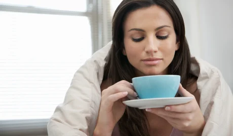 75394308 woman wrapped with duvet drinking tea