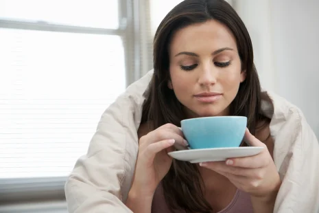 75394308 woman wrapped with duvet drinking tea