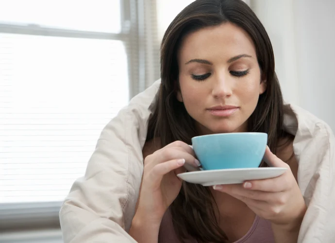 75394308 woman wrapped with duvet drinking tea