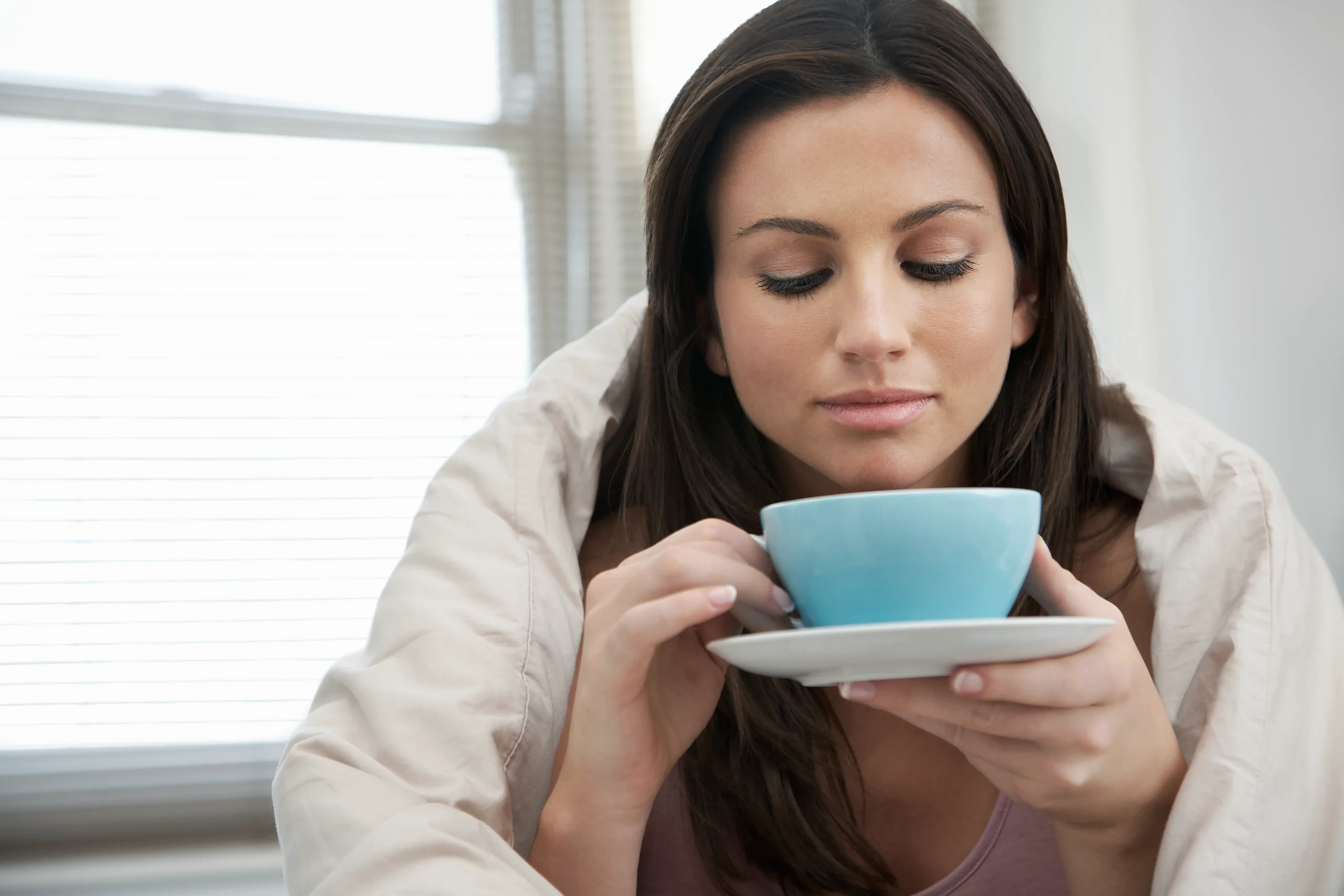 75394308 woman wrapped with duvet drinking tea
